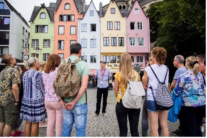 Tour guide giving explanations in front of colorful traditional houses